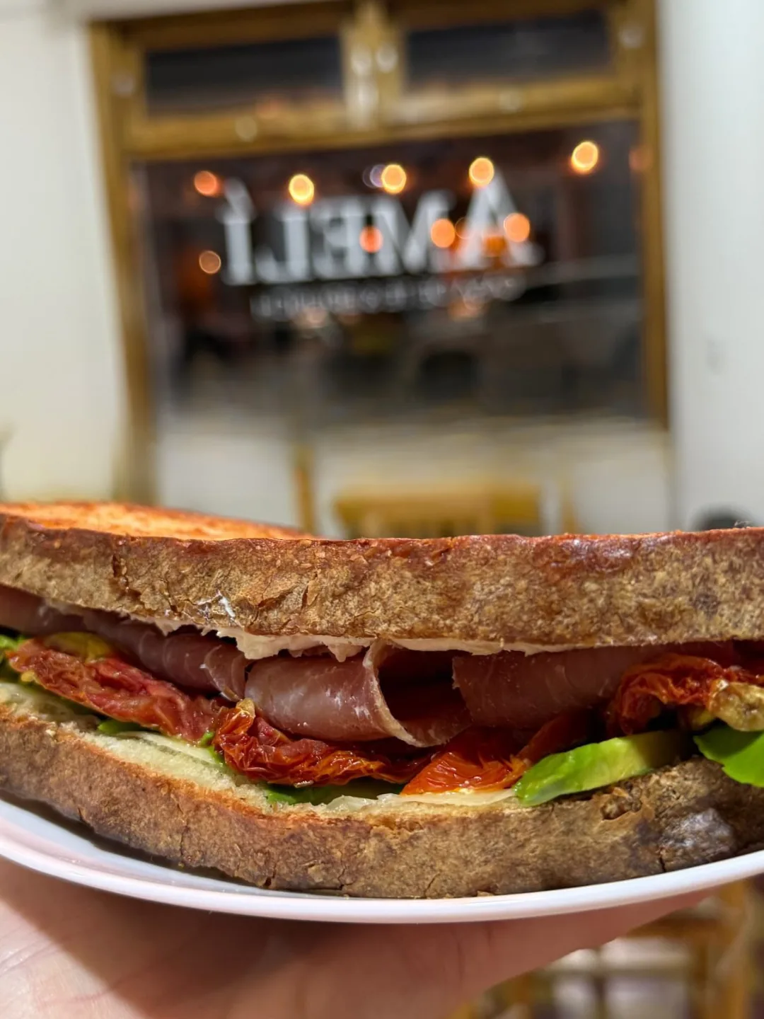 Sándwich de jamón crudo, tomates secos y rúcula en pan artesanal